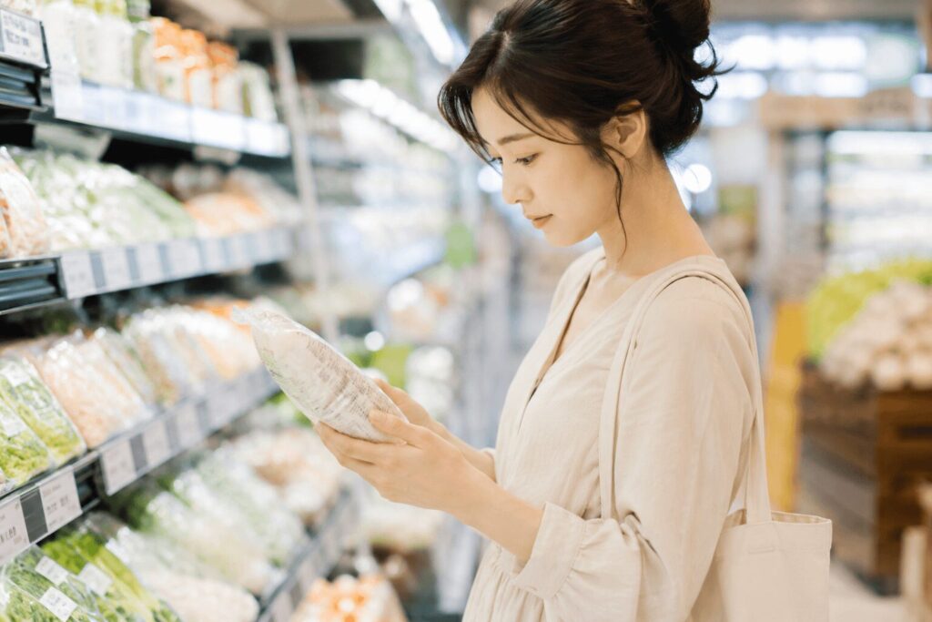 スーパーで原材料表示を確認する女性のイメージ